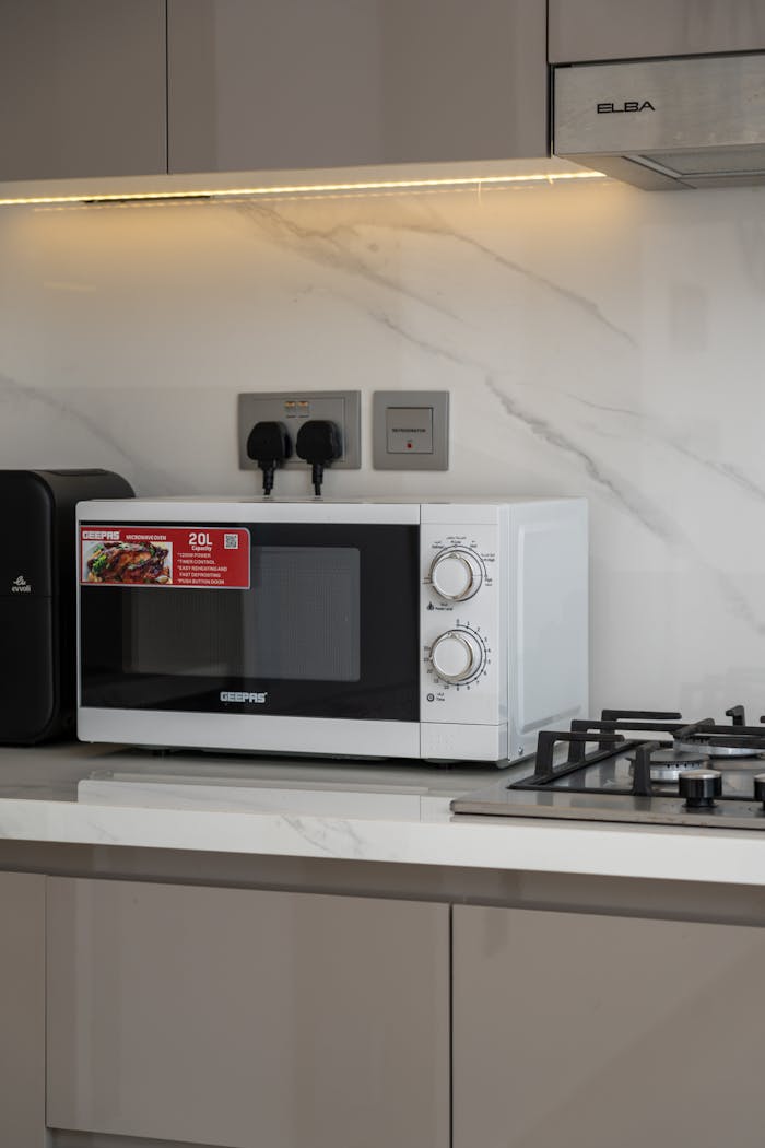 Contemporary kitchen space featuring a microwave and a gas stove on a marble countertop in Dubai